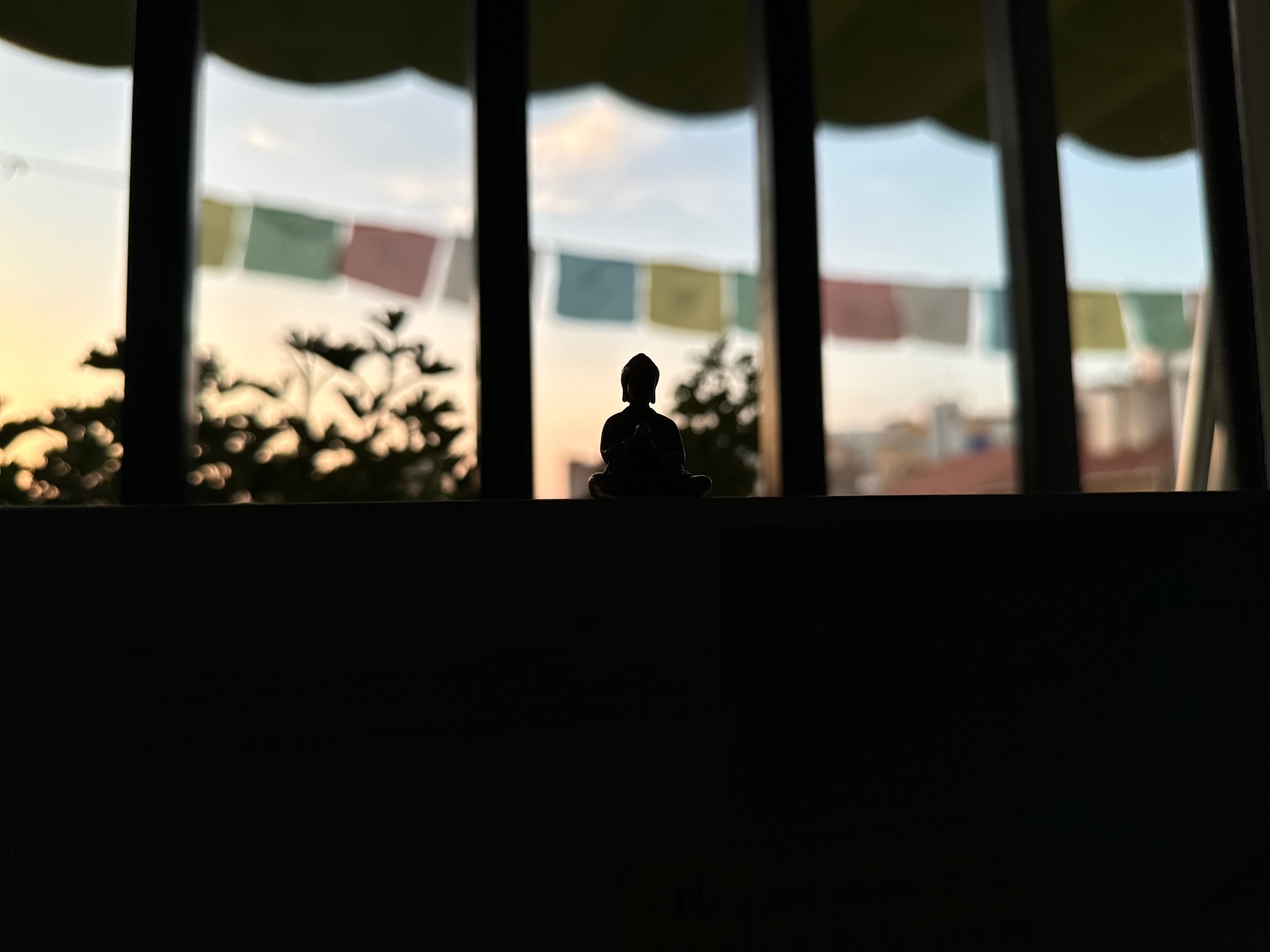 Desde el escritorio, una imagen del buda contrasta con las banderas de oración de la terraza